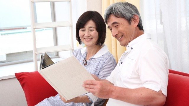 長年連れ添った夫婦が自宅の前で微笑んでいるイメージ・おしどり贈与